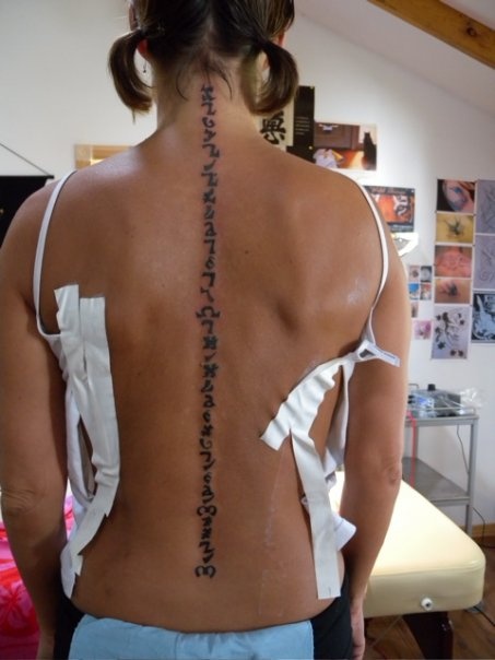 the back of a woman's upper body with writing on her left shoulder and right arm