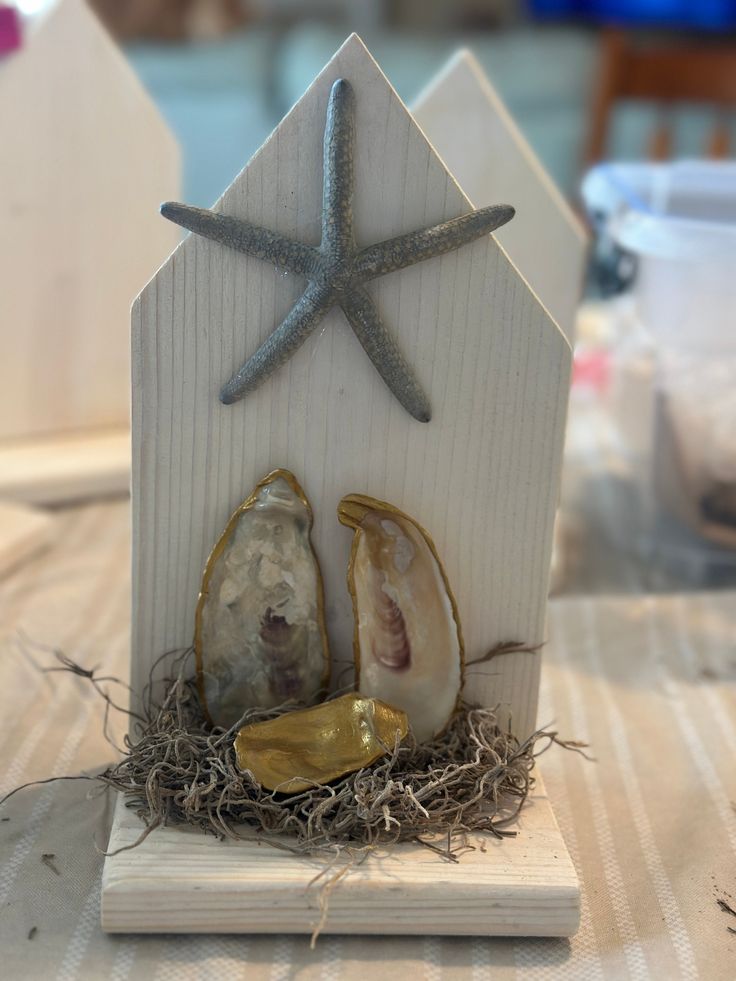 a small white house with shells and starfish on the roof is sitting on a table