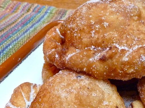 a pile of doughnuts sitting on top of a plate covered in powdered sugar