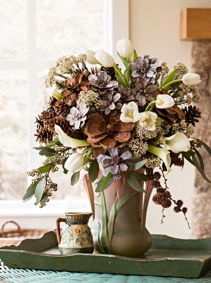 a vase filled with lots of flowers on top of a table next to a window