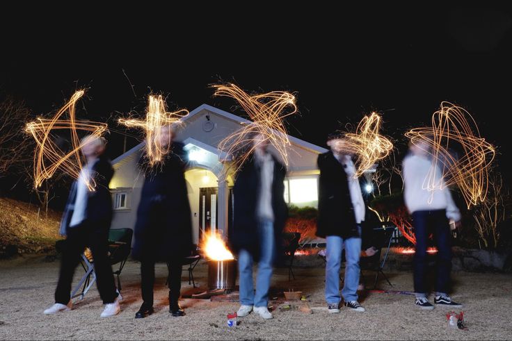 some people are standing in front of a house with sparklers on their heads and hands