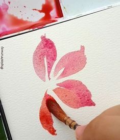 someone is using a brush to paint a flower with watercolors on the paper