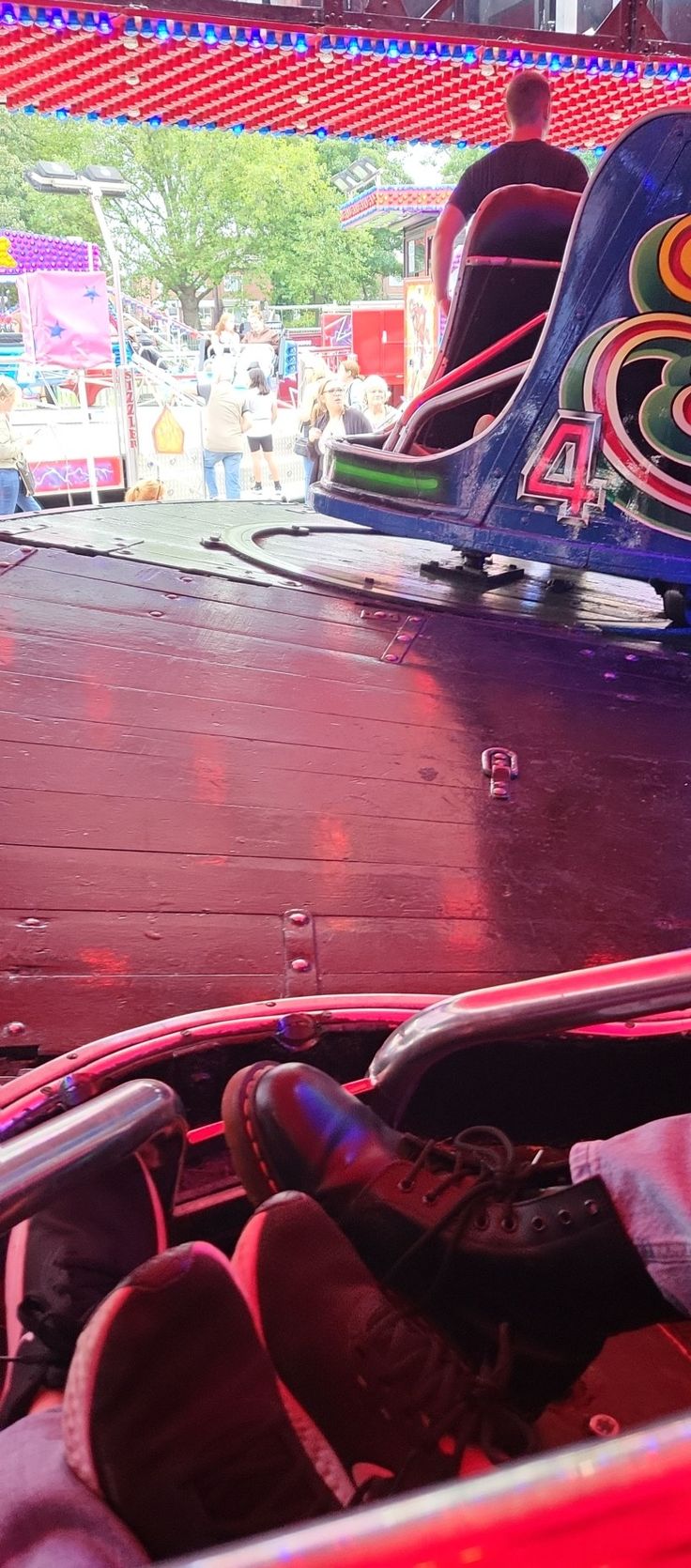 the inside of a carnival ride with people riding on it and two roller coasters in the background