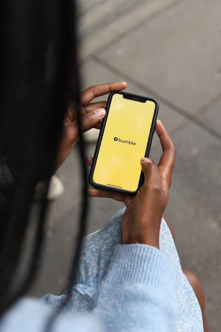 a person holding a yellow cell phone in their left hand and looking at the screen