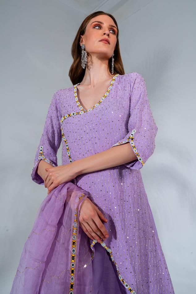 Lilac overlap kurta with mirror, thread and sequin embroidery and an asymmetric hem. Paired with a matching pant and dupatta.
Components: 3
Pattern: Embroidered
Type Of Work: Mirror, Thread, Pearl, Bead, Gota, Sequin
Neckline: Round
Sleeve Type: Three-quarter
Fabric: Kurta and Pant: Georgette, Dupatta: Organza
Color: Purple
Other Details: 
Asymmetric hem
Length:
Kurta: 32 inches
Pant: 38 inches
Closure:
Kurta: Zip
Occasion: Puja - Aza Fashions Purple Mirror, Georgette Dupatta, Mirror Round, Types Of Work, Sequin Embroidery, Kurta With Pants, Sequins Embroidery, Set For Women, Asymmetric Hem