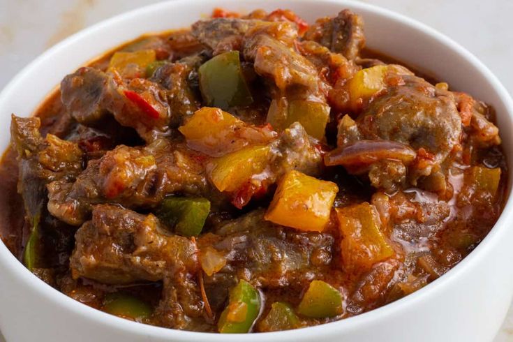 a white bowl filled with meat and vegetables