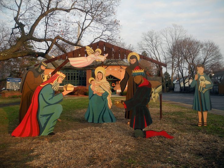 three nativity figures in front of a small christmas scene with the birth of jesus