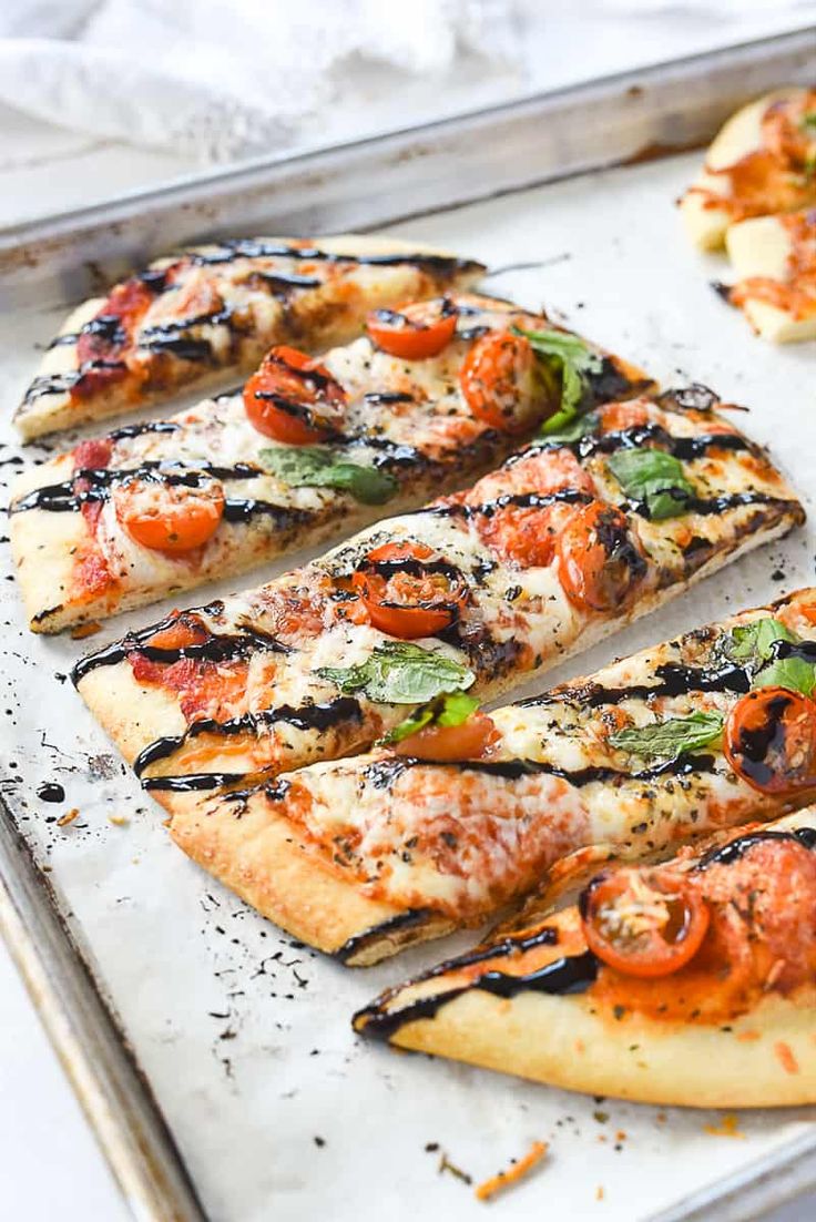 pizzas with tomatoes, basil and cheese on a baking sheet