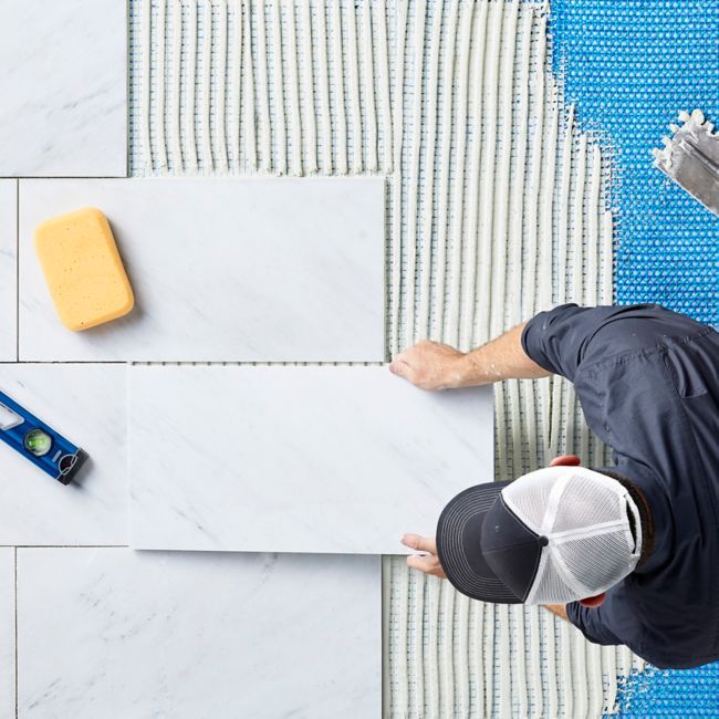 a man with a hat is working on some tile