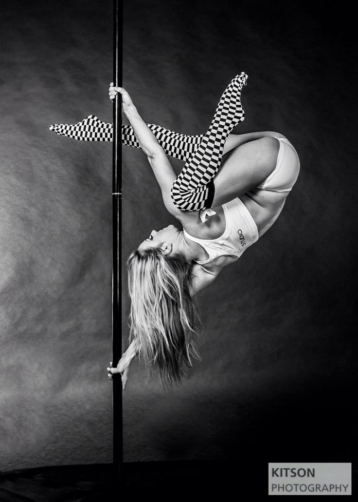 a woman is doing a handstand on a pole with her legs spread out