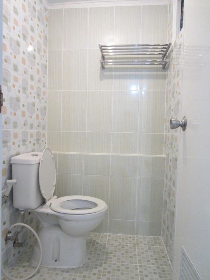 a white toilet sitting inside of a bathroom next to a shower head mounted on a wall