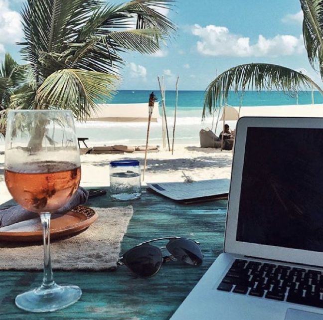 an open laptop computer sitting on top of a table next to a glass of wine