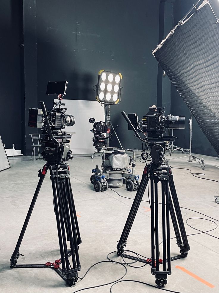 two cameras sitting on top of a tripod in a room next to other equipment