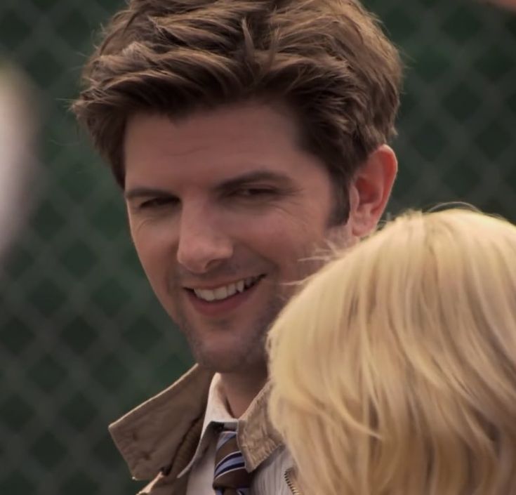 a man smiling while standing next to a blonde woman