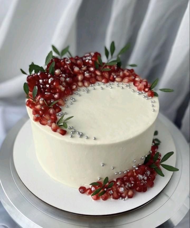 a white cake topped with berries and greenery