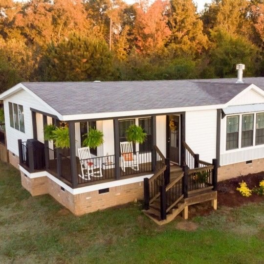 a mobile home sits in the middle of a grassy area with trees and shrubs around it