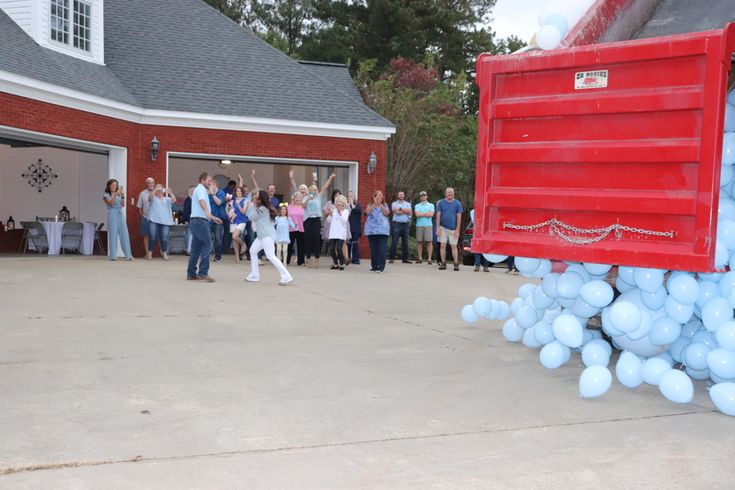 a group of people standing in front of a red truck with balloons attached to it