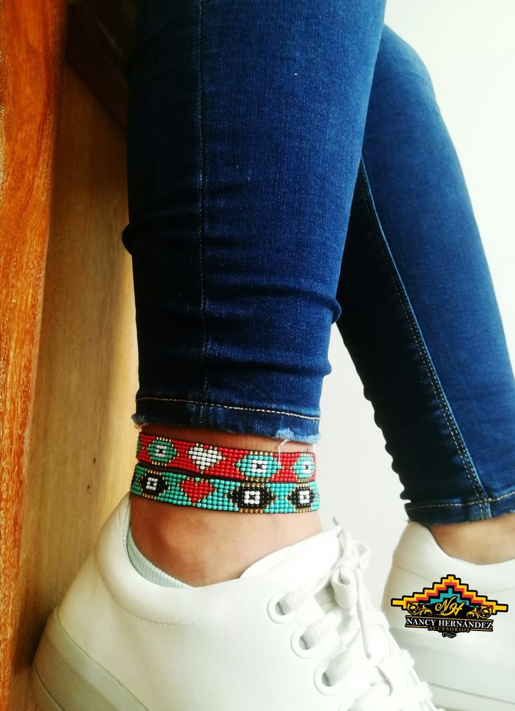 a close up of a person's foot wearing white sneakers and a colorful beaded bracelet