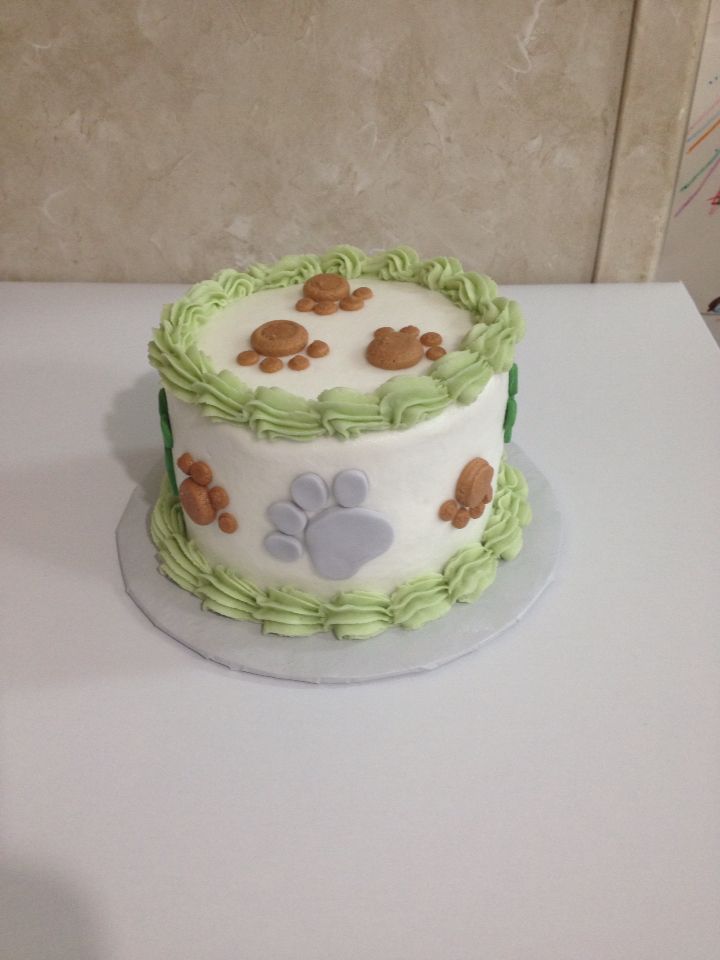 two tiered cake decorated with green and white icing on top of a table