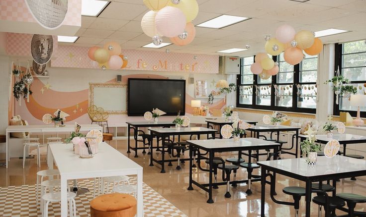 an empty classroom with tables and chairs in front of a television screen on the wall