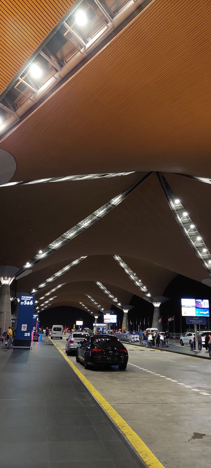 an airport terminal with cars parked under the awnings