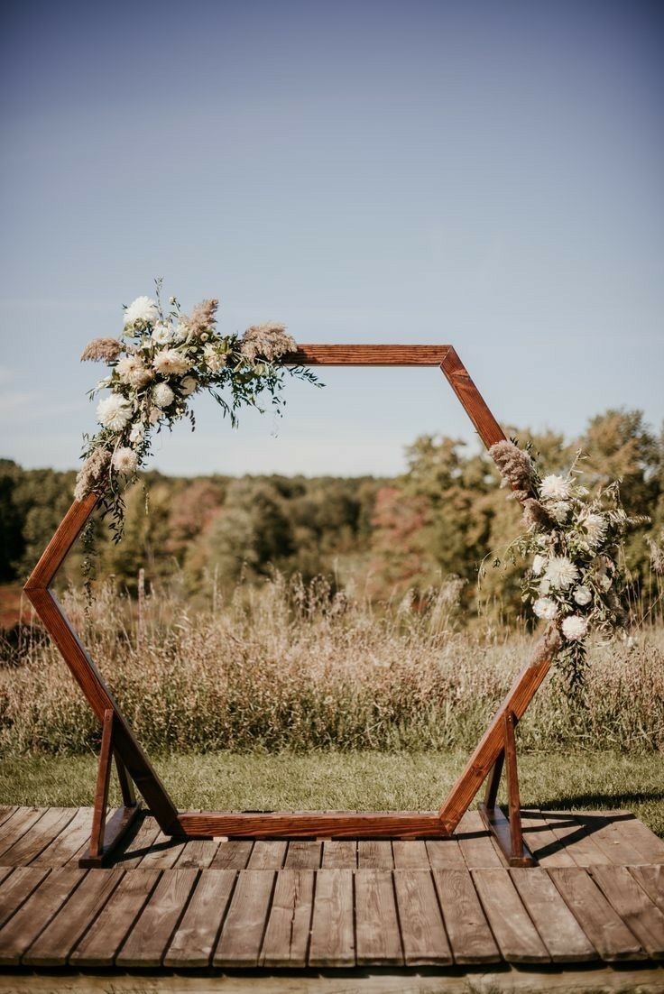 a wooden frame with flowers and greenery on the ground in front of an open field