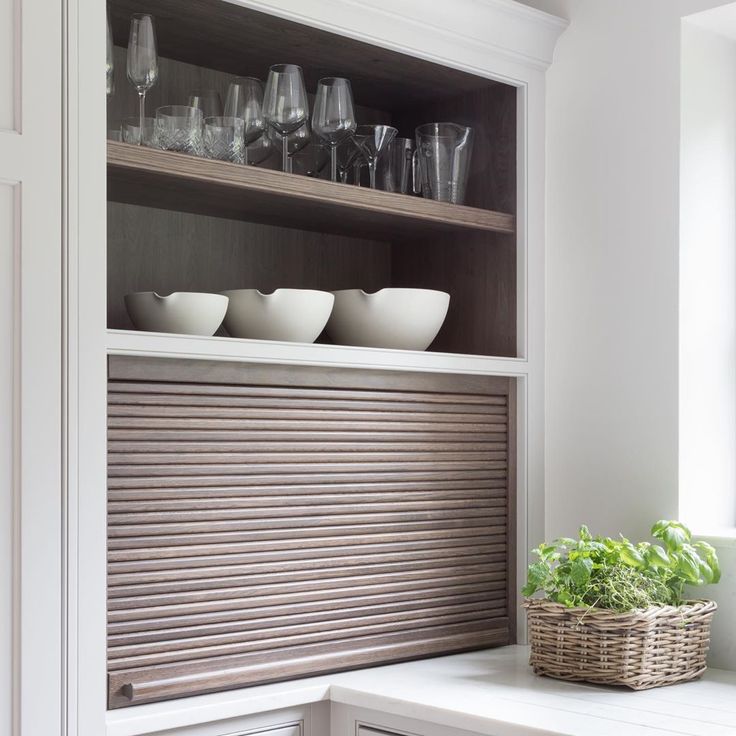 bowls and glasses are sitting on a shelf in the kitchen