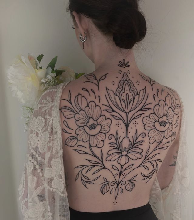 the back of a woman's body with tattoos on her upper and lower half