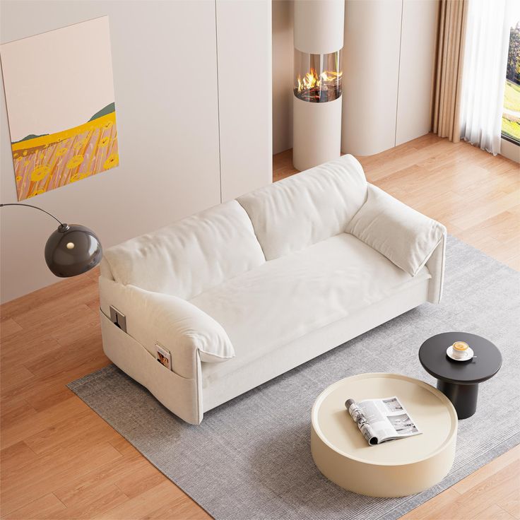 a white couch sitting on top of a hard wood floor next to a table and lamp