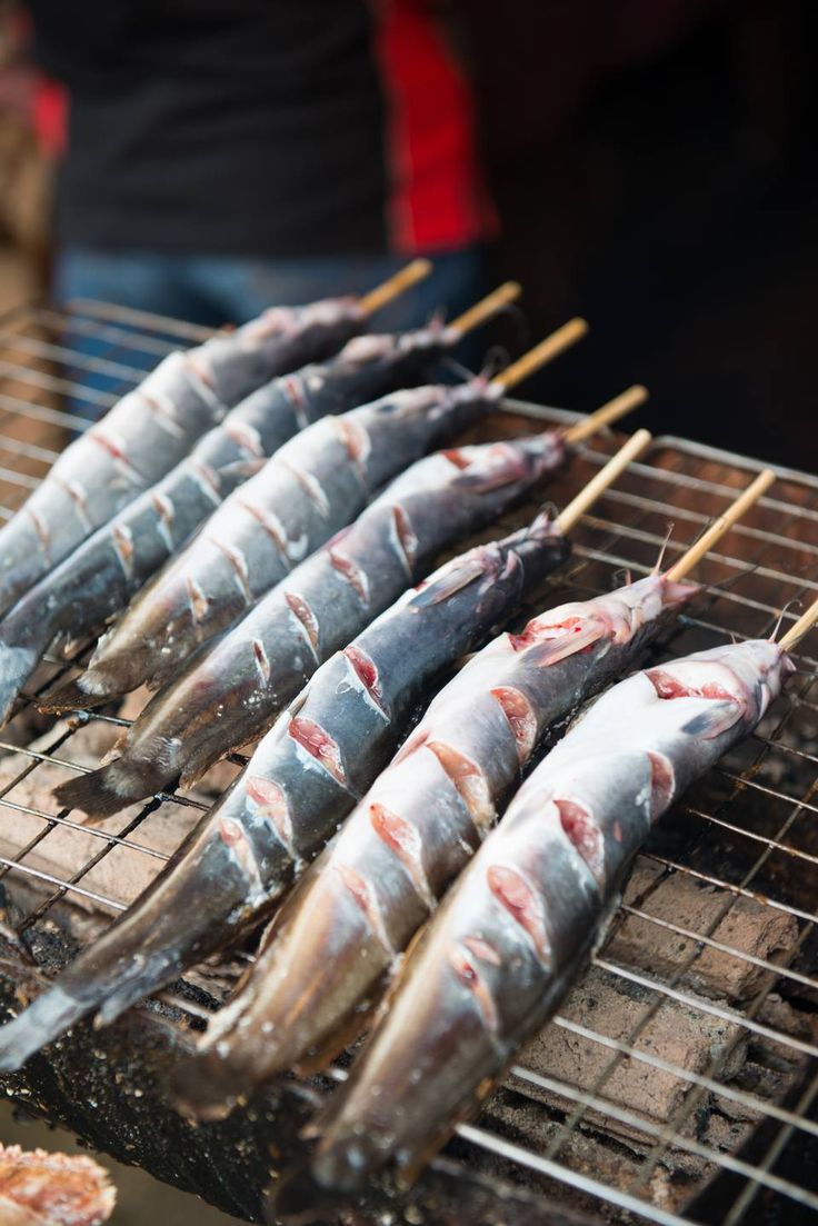 several fish are being grilled on a grill with toothpicks and other food items