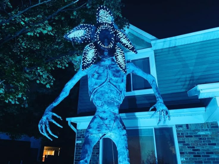 a statue of a man in front of a house with blue light on it's face