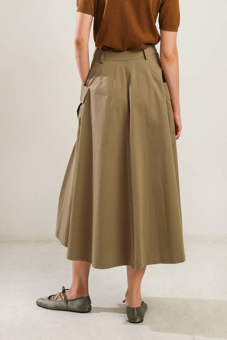 A solid woven full skirt featuring front closure and side pockets Details: Self : 100% Cotton Size & Fit - Model is 5`8" And Wearing Size Small- Measurements Taken From Size Small- Approx. Length: 33.5" Midi Skirt With Pockets For Work, Workwear Midi Skirt With Pockets, Chic Midi Cargo Skirt With Pockets, Chic Long Cargo Skirt With Pockets, Chic Cargo Midi Skirt With Pockets, Solid Color Midi Skirt With Pockets, Solid Color Relaxed Cargo Skirt With Pockets, Khaki Midi Skirt With Pockets, Relaxed Solid Cargo Skirt With Pockets