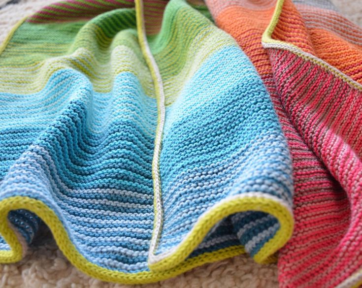 three knitted blankets laying on the floor next to each other