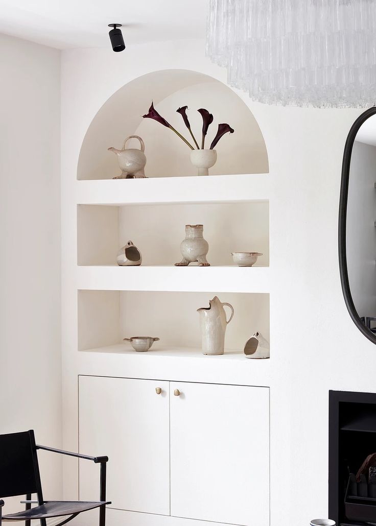 a living room with white shelves filled with vases