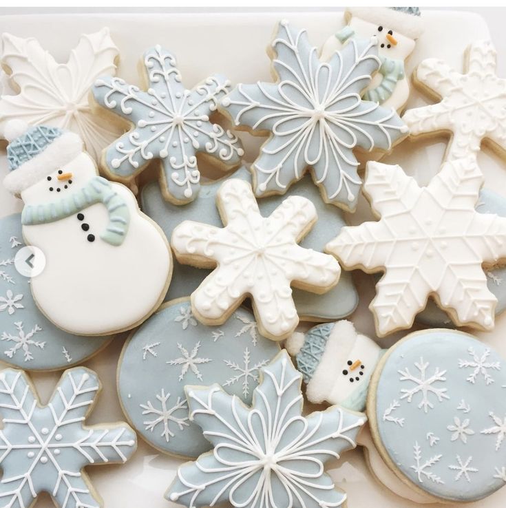 snowflakes, cookies and other holiday treats are arranged on a white plate with blue trim