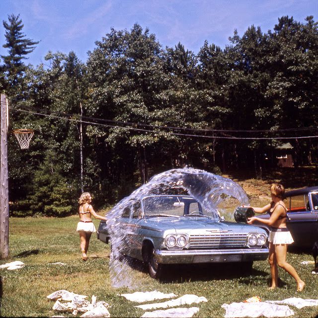 two women washing a car with a sprinkler