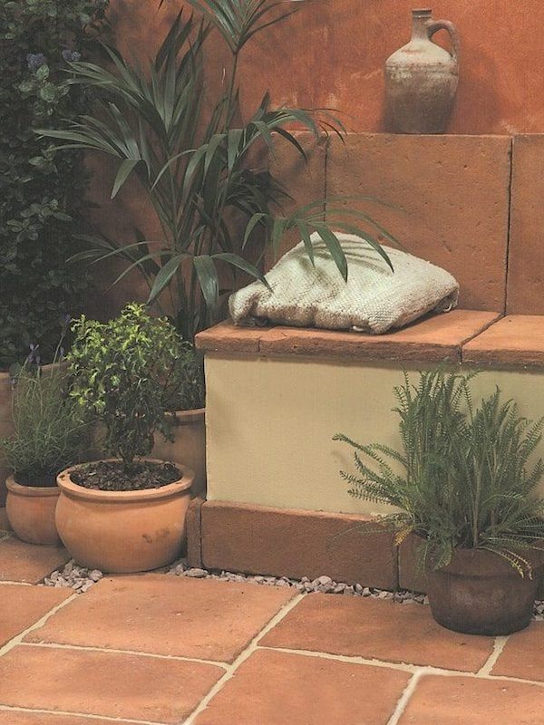 some potted plants sitting on the side of a stone wall next to a planter