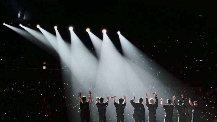 a group of people standing on top of a stage with their hands in the air