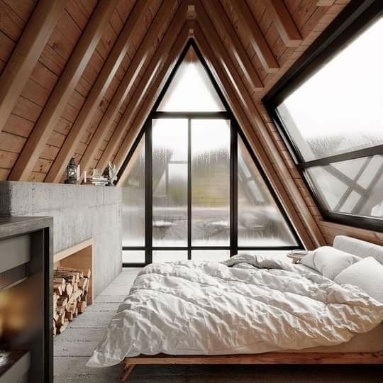 an attic bedroom with wooden walls and flooring is furnished with white bed linens