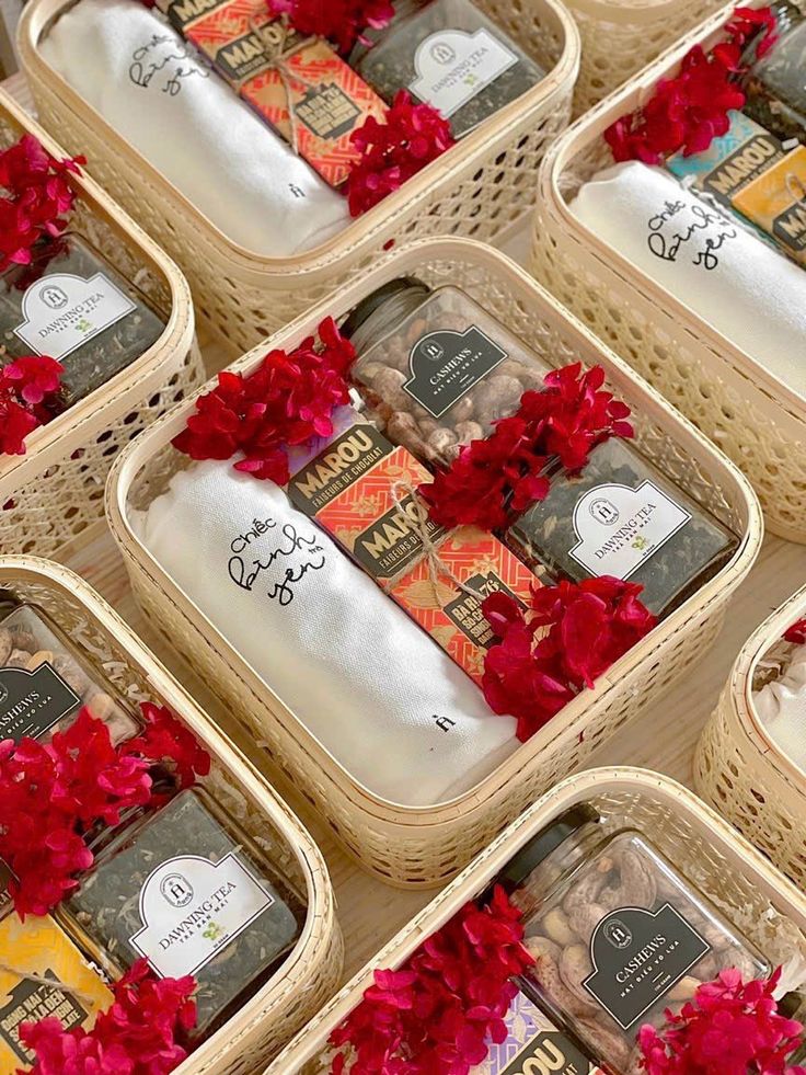 several baskets filled with different types of soaps and body scrubs on display in front of red flowers