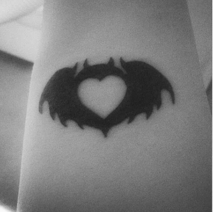 a black and white photo of a heart shaped bat tattoo