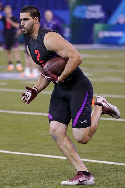 a man running with a football in his hand on the field during a game,