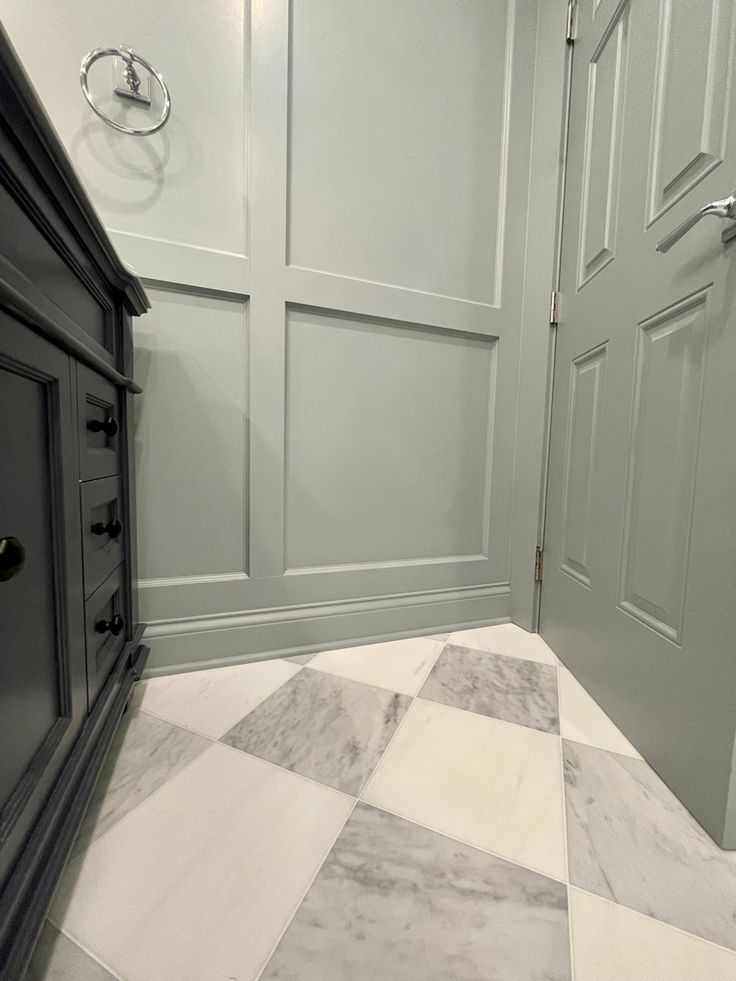 a white and grey bathroom with checkered tile flooring on the walls, and two doors leading to another room