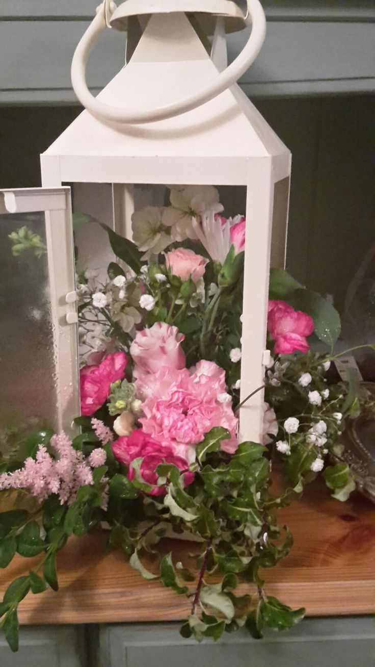 a white lantern with pink flowers and greenery