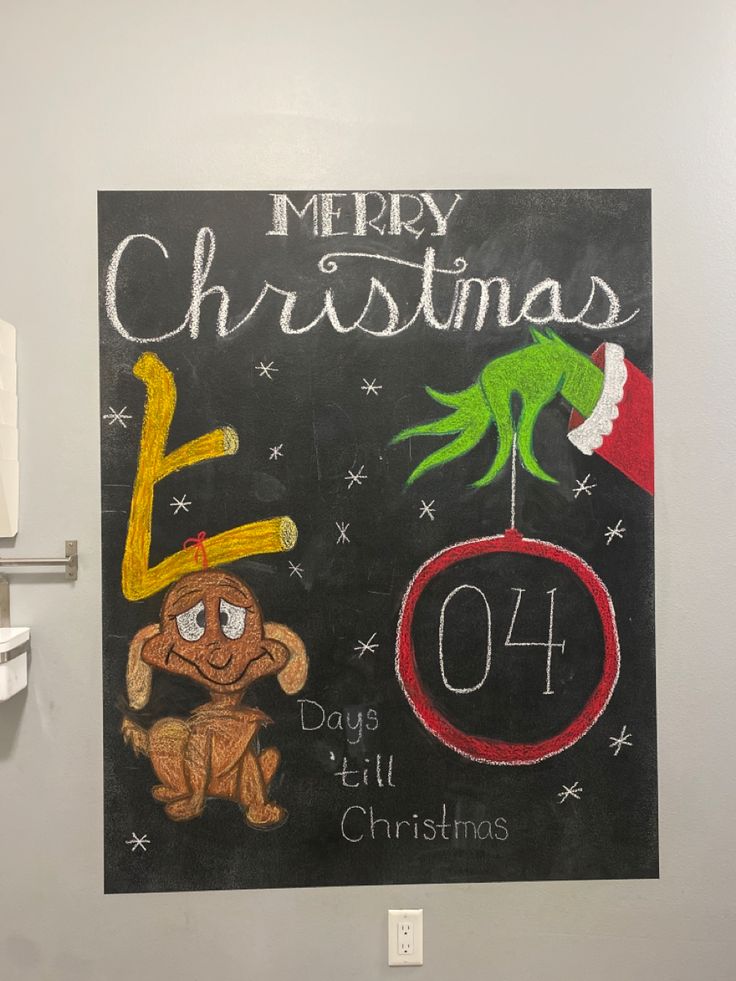 a chalk board with the words merry christmas written on it and an elf's hat