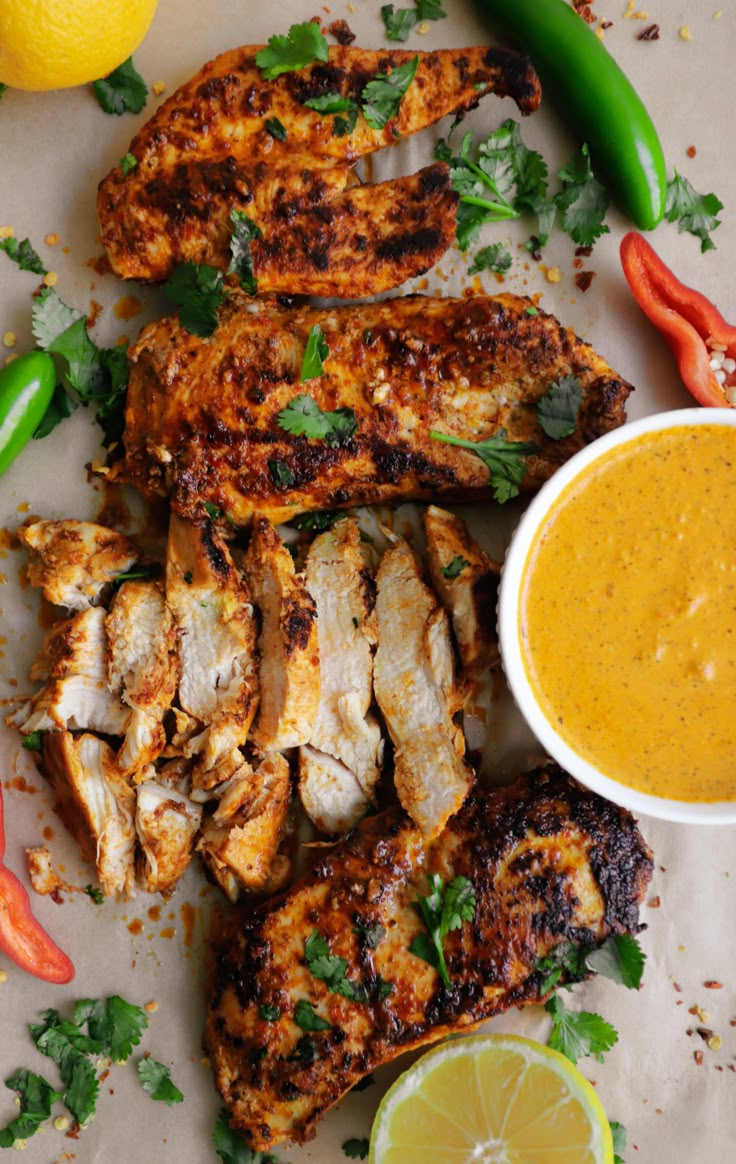 grilled chicken with orange sauce and garnishes on a plate next to peppers