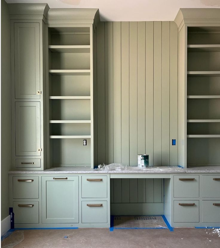 an empty room with green cabinets and blue tape on the floor in front of it