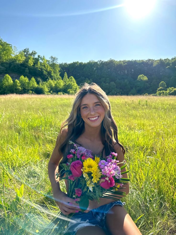 a woman sitting in the grass holding flowers