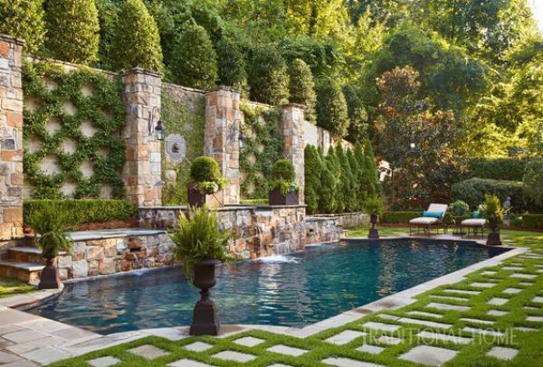 an outdoor swimming pool surrounded by grass and stone walls with seating areas around the pool