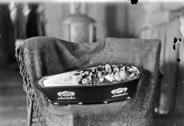 an old black and white photo of a suitcase with food in it sitting on a chair